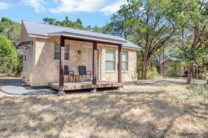 A stone cabin with a covered porch, two windows, and a chair outside. - Morning Dove I Romantic, Minutes from The Square! (Wimberley)