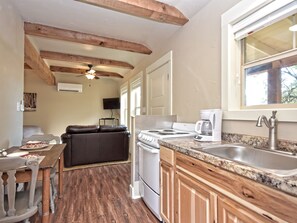 A compact kitchen with a stove, sink, and a dining area with a couch. - Morning Dove I Romantic, Minutes from The Square! (Wimberley)