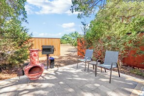 An outdoor patio with a barbecue grill, a hanging pottery piece, and two chairs. - Morning Dove I Romantic, Minutes from The Square! (Wimberley)