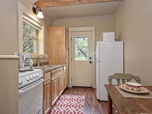 A compact kitchen with wooden cabinets, a white stove, a sink, and a refrigerator. - Morning Dove I Romantic, Minutes from The Square! (Wimberley)