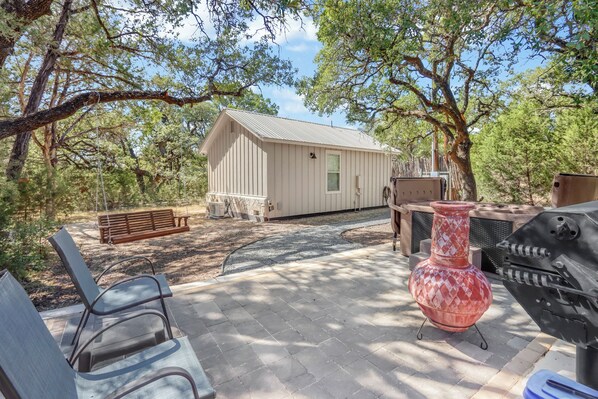 A patio with outdoor furniture, a grill, and a small shed.