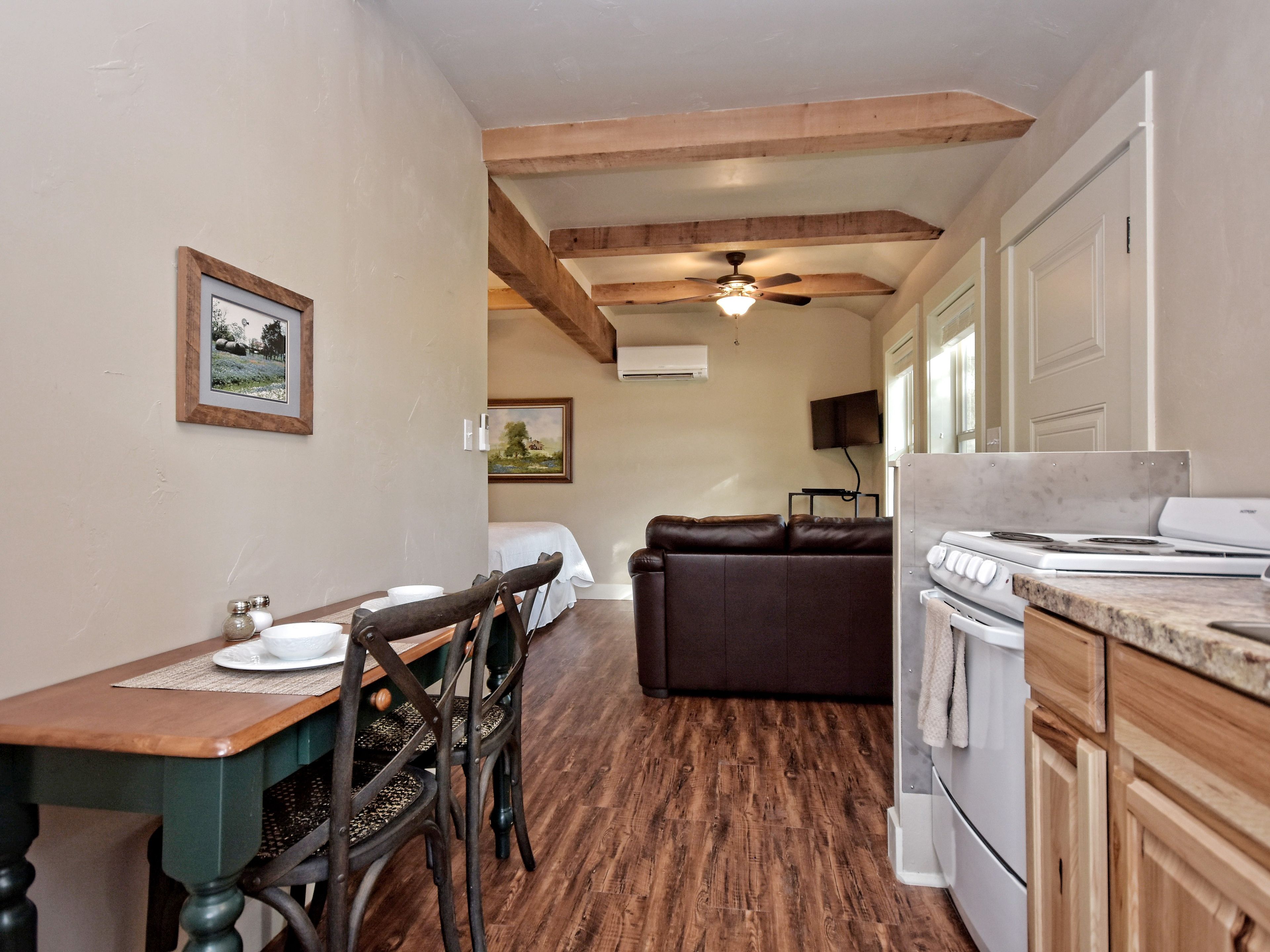 A kitchen with wooden cabinets, a stove, and a dining area with a table and chairs.