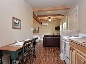 A kitchen with wooden cabinets, a stove, and a dining area with a table and chairs.