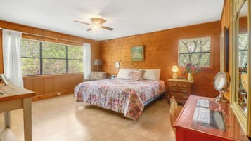 A bedroom with a bed, dresser, mirror, and windows with blinds.