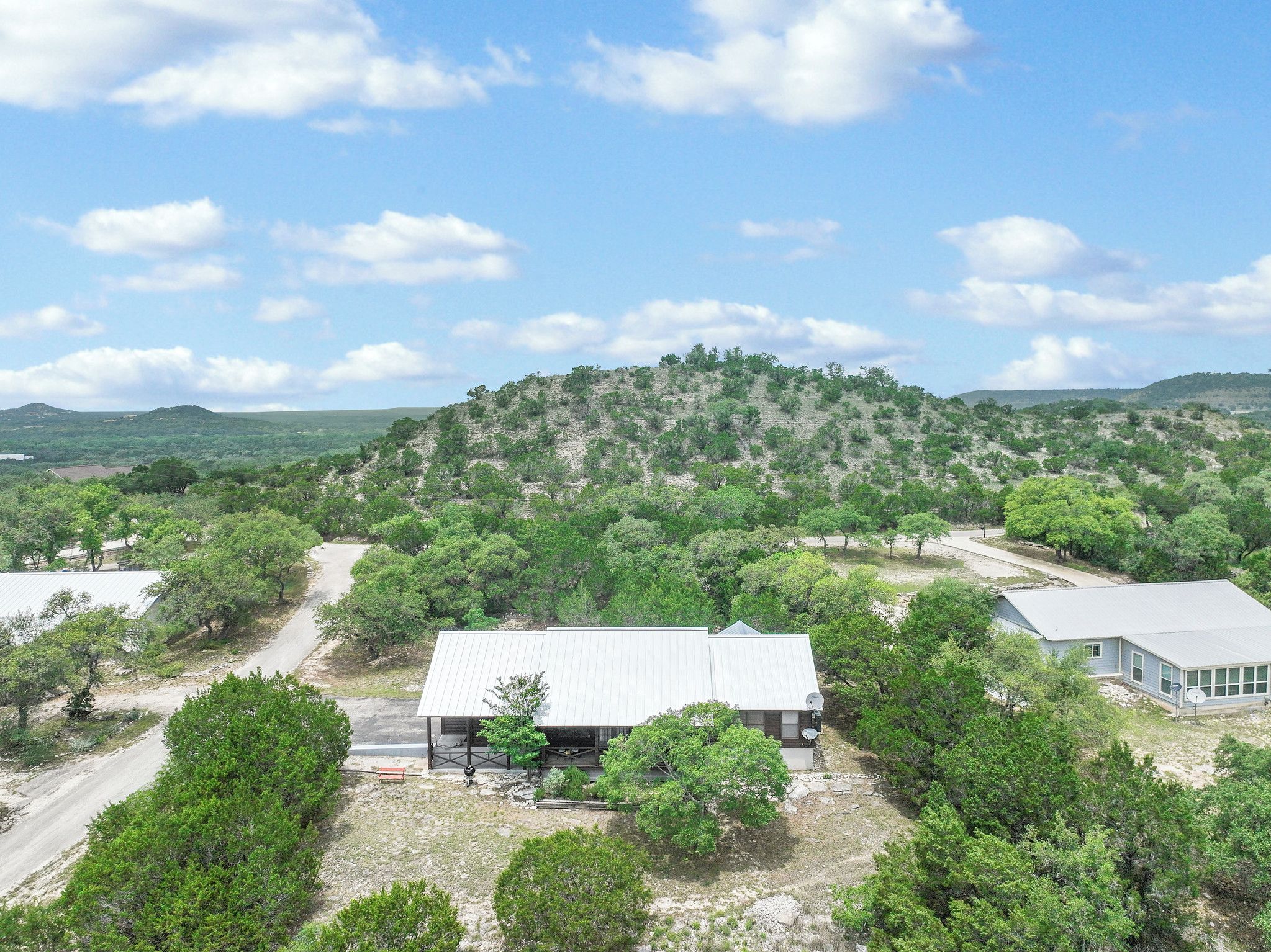 A building with a flat roof, surrounded by trees and a hilly landscape.