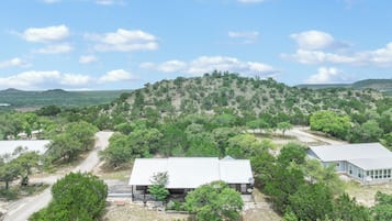 A building with a flat roof, surrounded by trees and a hilly landscape.