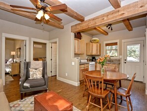 A spacious living area with a wooden ceiling, a dining table with chairs, a sofa, and a coffee table. - Mountain Laurel I 2Br Cabin near Square! (Wimberley)