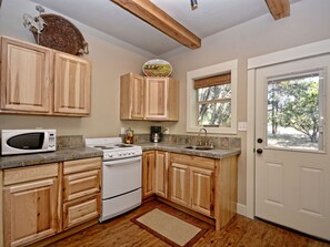 Una cocina con armarios de madera, un microondas, una estufa y un lavabo.