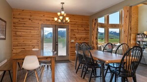 Ein Esszimmer mit Holzwänden, einem Chandelier, großen Fenstern und Bergblick.