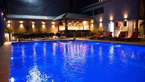 Piscina com espreguiçadeiras e um espaço de bar.