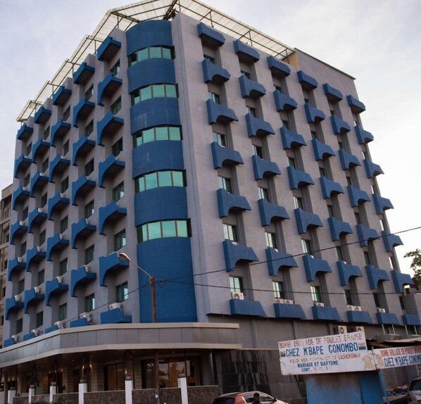 A multi-story building with a unique architectural design featuring protruding balconies and a curved facade. - Hotel Sonia (Ouagadougou)