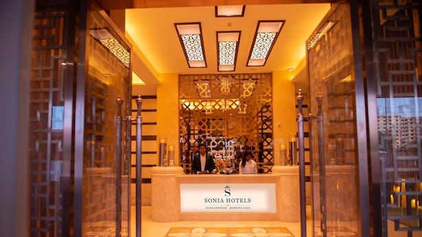 A reception area with a sign for Sonia Hotels, featuring a patterned floor and decorative lighting.