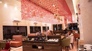 A restaurant with a buffet setup, seating arrangements, and a decorative ceiling.