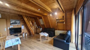 A cozy wooden interior with a TV, sofa, and dining table. - Vacation cottage Stern, Germany (Wittmund)