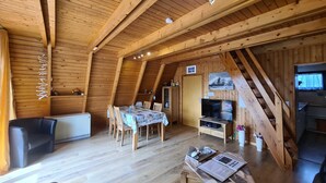 A cozy, wooden interior with a dining area, a TV, and a fireplace. - Vacation cottage Stern, Germany (Wittmund)