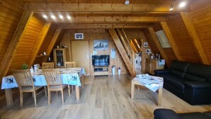 A cozy attic room with a dining table, chairs, a sofa, and a TV. - Vacation cottage Stern, Germany (Wittmund)