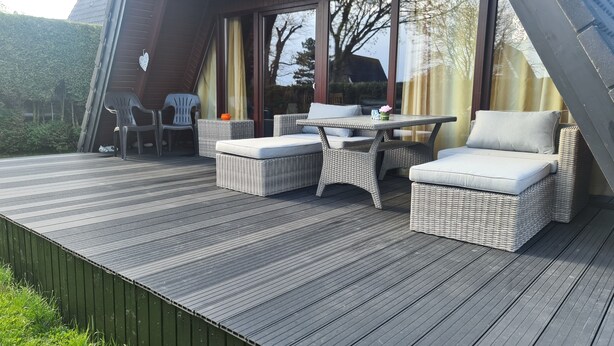 A modern outdoor deck with wicker furniture, a table, and chairs. - Vacation cottage Stern, Germany (Wittmund)