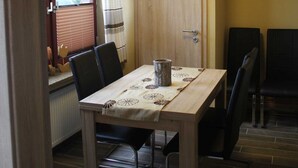 A dining area with a wooden table, black chairs, and a clock on the wall.