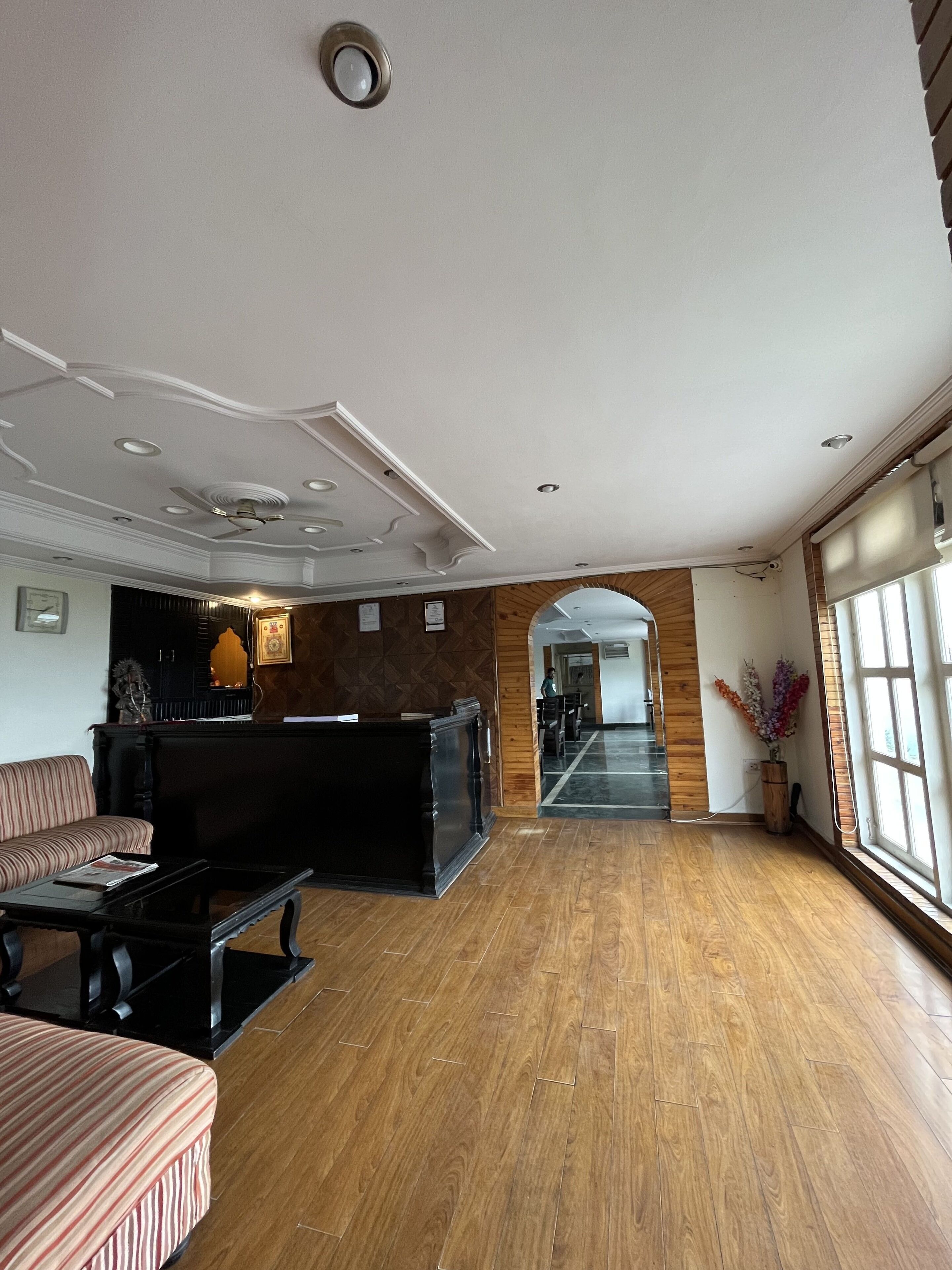 Een ruime lobby met een receptiebalie, een zithoek en een houten vloer.