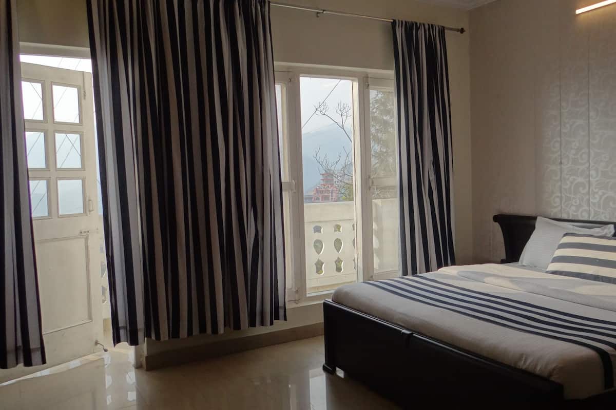 A bedroom with a bed, curtains, a window, and a view of a building outside.