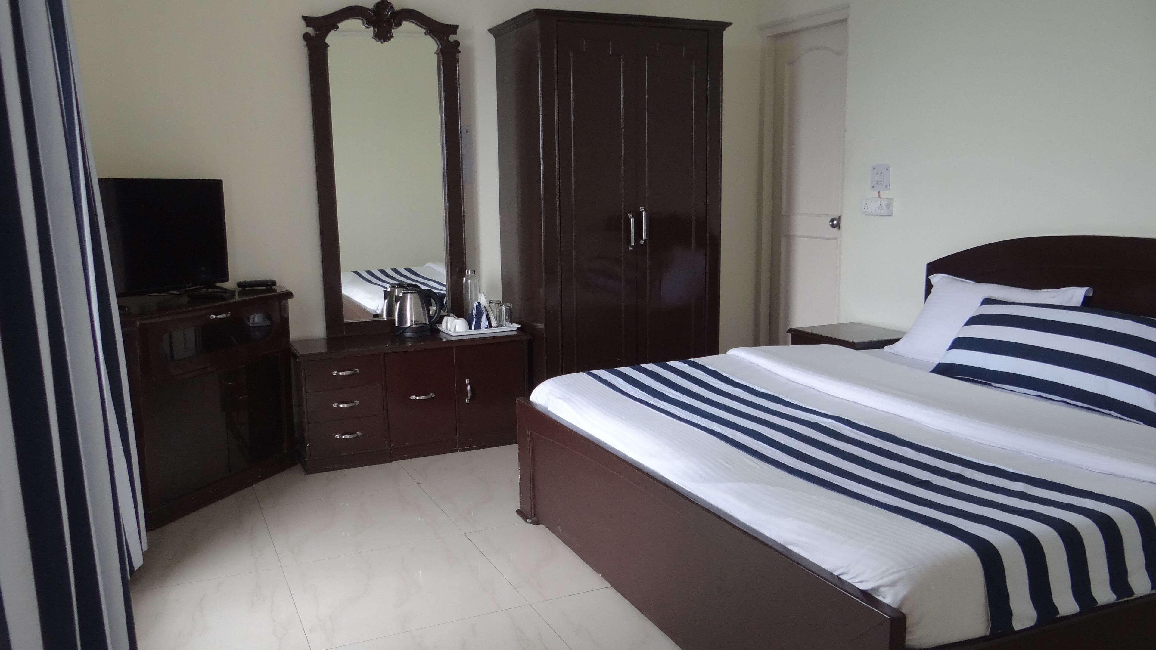 Habitación de hotel con cama, cómoda, espejo y televisión.