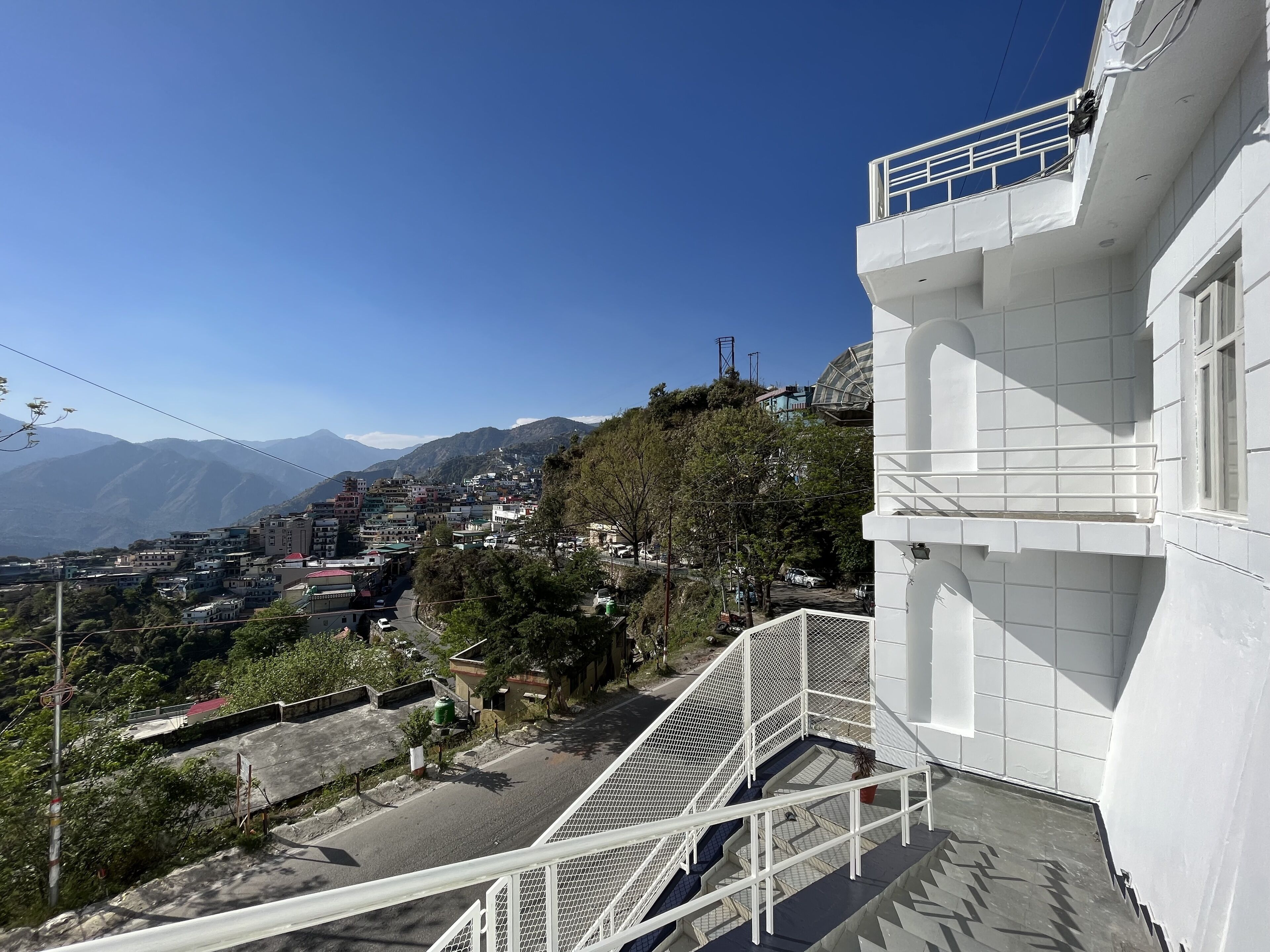 Zona residencial con un edificio blanco que tiene un balcón y una escalera.