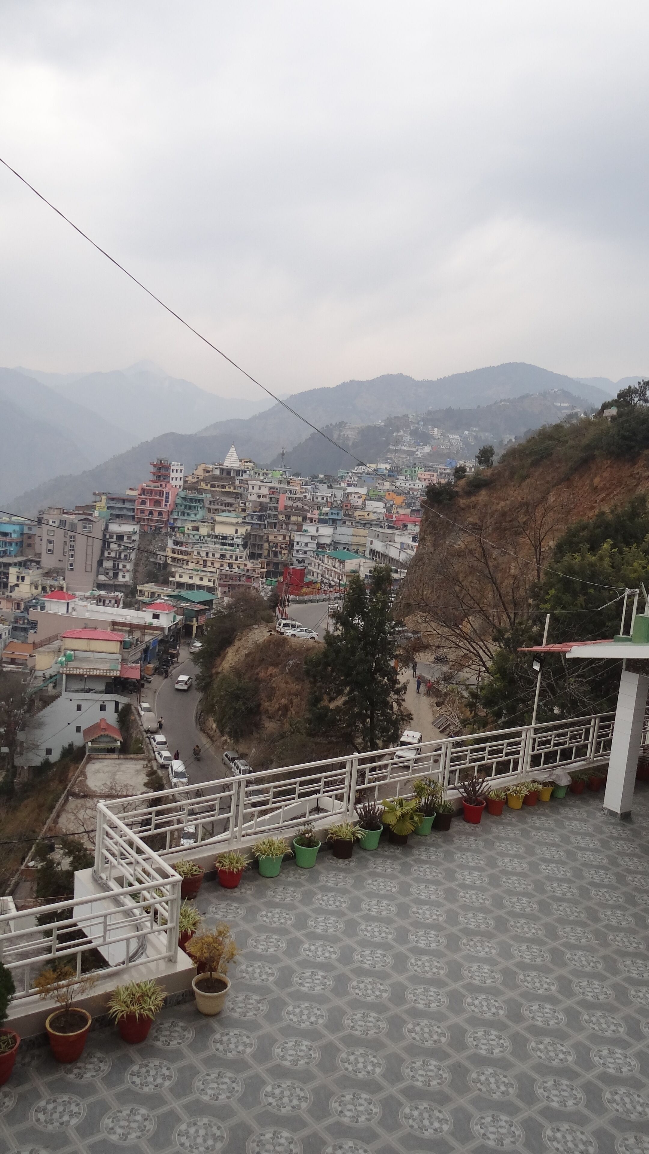 A residential area with multi-story buildings, a road, and a hilly landscape in the background.