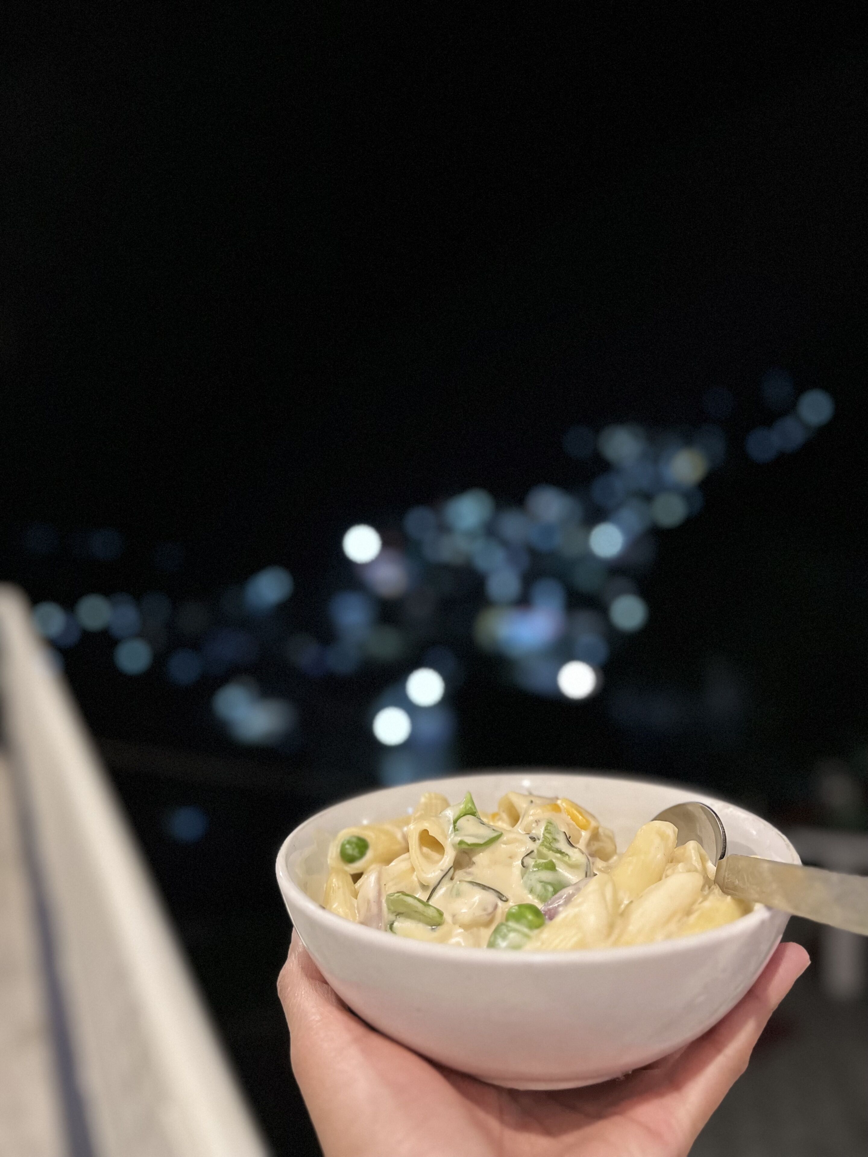 Un plato de pasta con una cuchara, sostenido por una persona.