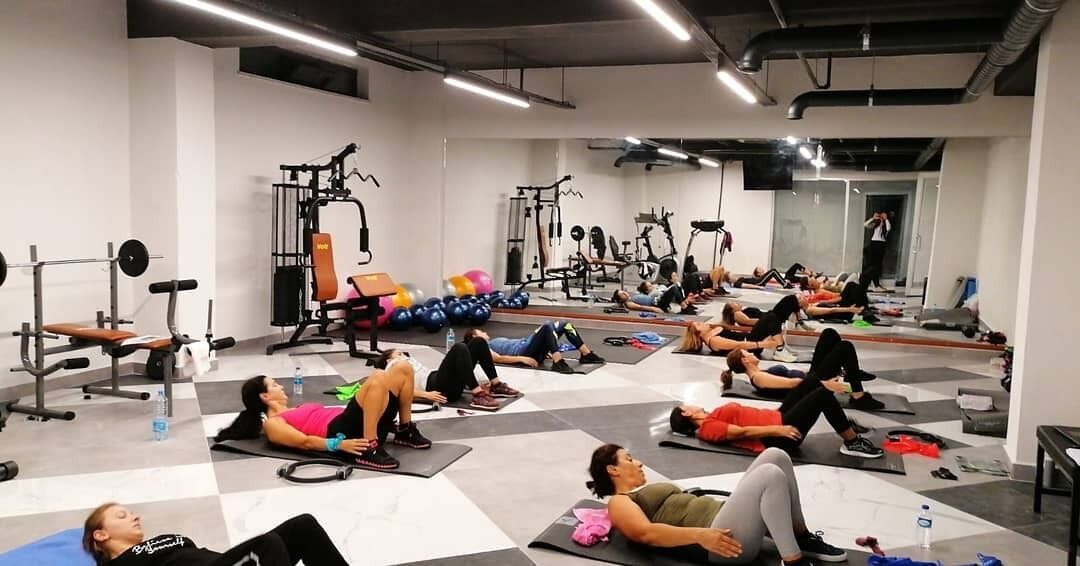 A gym with various exercise equipment and people lying on mats.