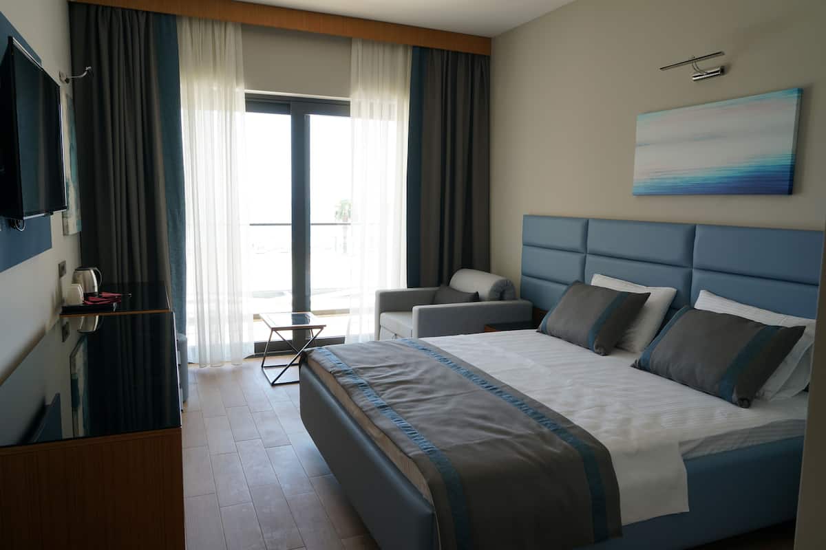 Une chambre d’hôtel moderne dotée d’un grand lit, d’une télévision à écran plat, d’un coin salon et offrant une vue sur l’extérieur.