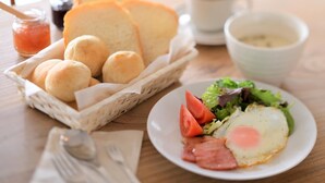 A breakfast setting with bread rolls, a plate of eggs, tomatoes, lettuce, and ham, along with a cup of coffee and a jar of jam. - Cafe&Guest House Kaziya (Ichinoseki)