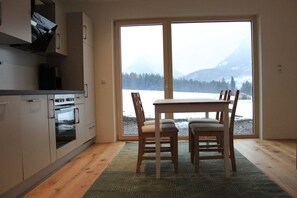 A kitchen with a large window, a dining table with chairs, and a view of a snowy landscape.