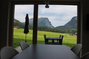Una habitación con un ventanal que ofrece vistas a una montaña y un campo verde.