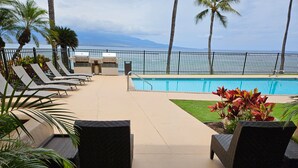 Un espace aménagé au bord de la piscine, avec des chaises longues, une piscine et une vue sur l’océan.