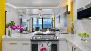 A modern kitchen with a large island, a view of the sea, and a dining area with a view. - Sea La Vie Secluded Oceanfront condo, Magical Sunrise romantic honeymoon Getaway (Wailuku)