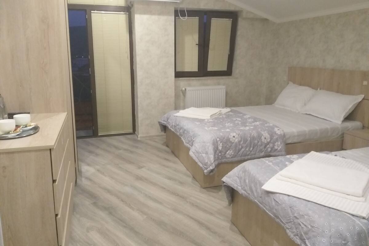 A bedroom with two beds, a wooden dresser, and a radiator.