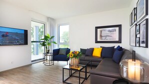 A modern living room with a sofa, a coffee table, and a TV mounted on the wall.