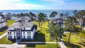 A residential area with modern houses, a well-maintained lawn, and a view of the sea.