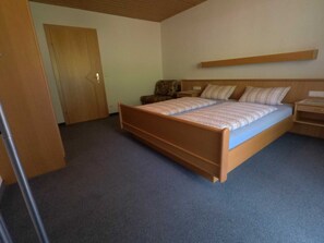 Un dormitorio con una cama individual, cabecera de madera, mesita de noche y una silla.
