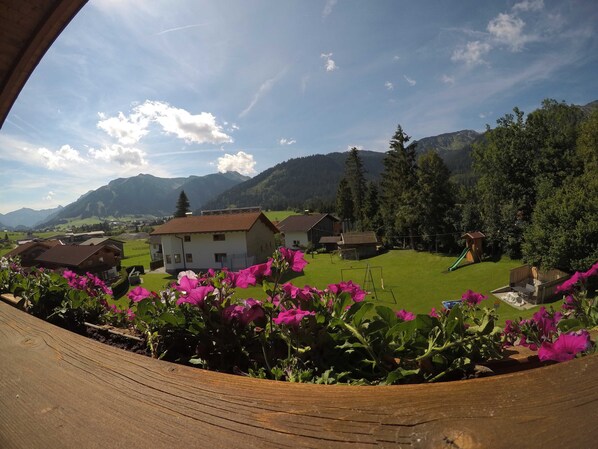 Un pueblo rural con casas, un parque infantil y montañas al fondo.