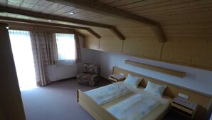 Un dormitorio con una cama grande, una silla, una mesita de noche y una ventana con cortinas.