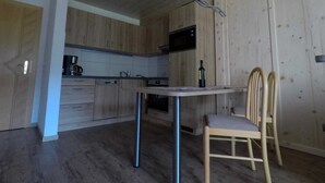 A kitchen with wooden cabinets, a microwave, and a dining table with chairs. - Suite - guest house Reichle (Untergschwend)