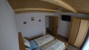 A bedroom with two single beds, a wooden wardrobe, a television on the wall, and a mirror. - Suite - guest house Reichle (Untergschwend)
