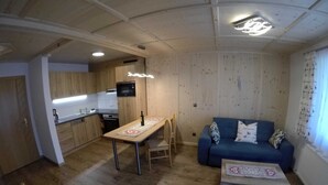 A compact living space with a kitchenette, a dining table, a sofa, and a small coffee table. - Suite - guest house Reichle (Untergschwend)
