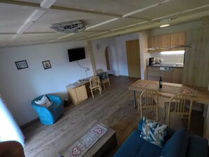 Ein kompakter Wohnbereich mit einer Küchenzeile, einem Essbereich und einer Sitzecke mit Sofa und Sesseln.