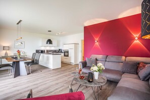 Una sala de estar moderna con un sofá gris, una mesa de centro y un comedor con mesa y sillas de madera.