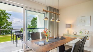A modern dining area with a glass table, leather chairs, and a view of the outdoors. - Apartment Mohnblume - Oasis on the lagoon - Mohnblume (5-3) (Garz/Usedom)
