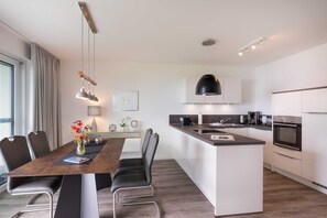 Una cocina moderna con una isla central, electrodomésticos integrados y un comedor con mesa y sillas.