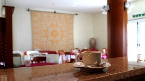 Una taza de café sobre una encimera de granito en el vestíbulo de un hotel, con una pared estampada y pilares de madera.