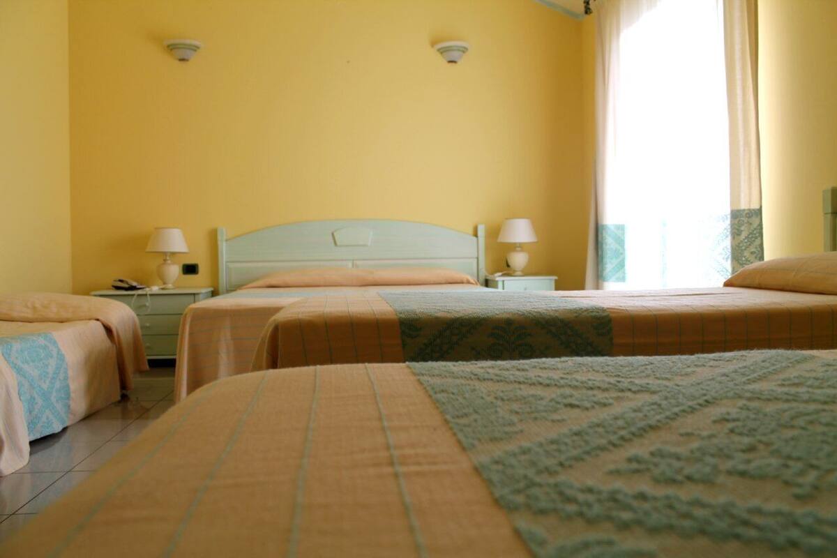 Una habitación de hotel con dos camas, cada una con cabecera y mesitas de noche a juego.